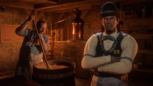 Un personnage jouable de Red Dead Online croisons les bras dans le sous-sol de la distillerie clandestine, Marcel produit de l'alcool à l'arrière plan.