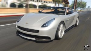 Image présentant une vue avant de la voiture de sport anglaise, Dewbauchee Massacro, roulant sur l'autoroute ouest de GTA Online. Le bolide est peint en gris clair.