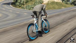 L'arrière du vélo de course "Tri-Cycles", le cadre du vélo est de couleur blanche avec des lignes bleues, du même bleu qui cercle l'intérieur des pneus. Également, le cadre du vélo dispose de l'inscription "Tri-Cycles".