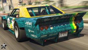 Vue arrière d’une voiture de course Declasse Tampa Drift jaune et verte pétrole en mouvement dans le jeu vidéo GTA Online. Le numéro ‘66’ est clairement visible sur le côté de la voiture. Plusieurs logos, y compris ‘ATOMIC’, ‘FUKARU’, ‘CHEPALLE’, ‘DECLASSE’ sont visibles sur différentes parties de la carrosserie de la voiture. Une phrase ‘You’d Be Batty Not’ est partiellement visible sur l’aileron arrière de la voiture.