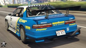 Cette image montre une voiture de course bleue et blanche, étiquetée comme ‘Annis Remus’, en mouvement sur une route. La voiture a divers autocollants et étiquettes de sponsors, y compris ‘Premier’, ‘TWIN AIRBAGS’, et ‘LABEL’. Le numéro 11 est affiché de manière proéminente sur le côté de la voiture. L’arrière de la voiture présente un grand aileron noir. Il y a une plaque d’immatriculation à l’arrière qui indique ‘RSG ACTU’. L’arrière-plan est flou en raison du mouvement de la voiture, indiquant la vitesse.