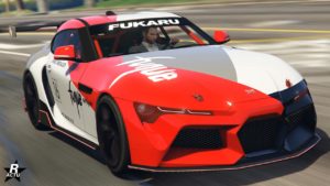 Image d’une voiture de course virtuelle d’un jeu vidéo, il s'agit de la Dinka Jester RR dans GTA Online. La voiture est principalement blanche et rouge, avec des détails noirs et des autocollants de marque. Elle a un design moderne avec des caractéristiques aérodynamiques, de grandes prises d’air à l’avant, et un kit de carrosserie large. Le mot ‘FUKARU’ est affiché de manière proéminente sur le pare-brise ; divers autres logos et textes sont visibles sur la carrosserie de la voiture mais ne sont pas entièrement lisibles en raison du flou de mouvement ou de l’angle. L’arrière-plan est flou en raison du mouvement de la voiture, indiquant qu’elle se déplace à grande vitesse.