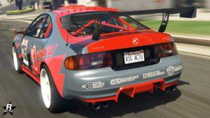 Cette image représente une vue arrière de la voiture Karin Calico GTF dans le jeu vidéo GTA Online. La voiture a une couleur de base grise avec un toit rouge et des décalcomanies rouges et noires, y compris le mot FUKARU sur le côté. Elle est équipée d’un grand aileron noir à l’arrière pour l’aérodynamique. Des logos et des textes sont visibles sur la carrosserie de la voiture, indiquant diverses marques fictives et des caractéristiques techniques.