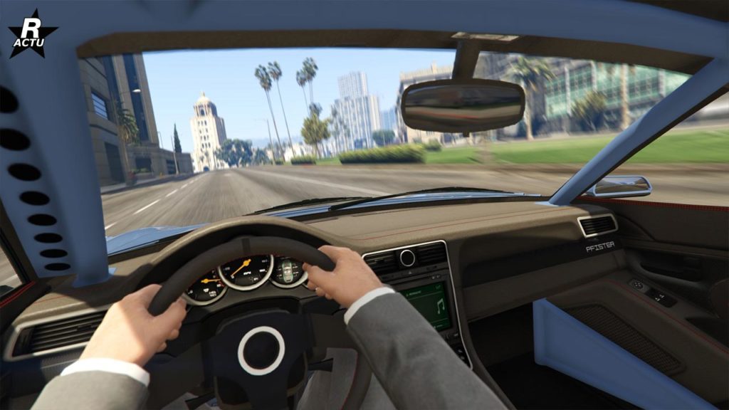 Cette image est une vue de l’intérieur de la Pfister Comet S2 dans GTA Online, montrant le tableau de bord avec des finitions, dont du carbone, un volant noir marqué du logo Pfister, et un écran d’infodivertissement sur la droite. À travers le pare-brise, on aperçoit une route bordée de palmiers et des bâtiments au loin sous un ciel bleu clair.
