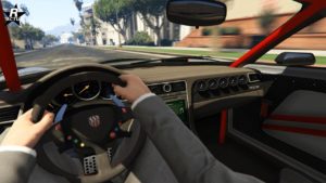 Cette image montre la vue intérieure du point de vue du conducteur d’un véhicule Pfister Growler dans le jeu vidéo GTA Online. Le volant dispose du logo Pfister au centre. Le tableau de bord comprend divers jauges et cadrans, et il y a un affichage numérique sur la console centrale. L’intérieur présente des accents rouges et des textures en fibre de carbone, renforçant son design sportif.