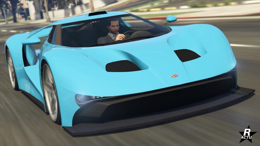 Vue de face d’une voiture de sport Vapid FMJ de couleur bleu clair en mouvement sur une rue de Los Santos dans GTA Online, mettant en valeur son design aérodynamique avec de grandes entrées d’air et une double grille noire sur le capot du véhicule.