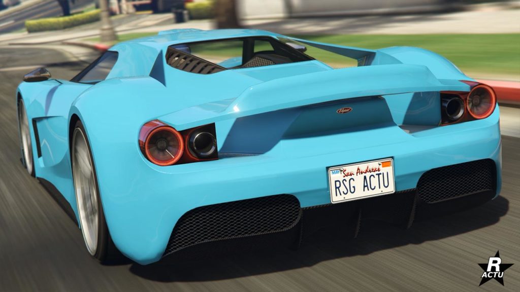 Vue arrière d’une voiture de sport Vapid FMJ de couleur bleu clair en mouvement sur une route dans GTA Online, mettant en évidence ses feux arrière circulaires distinctifs et un aileron plat. La plaque d’immatriculation indique ‘RSG ACTU’.
