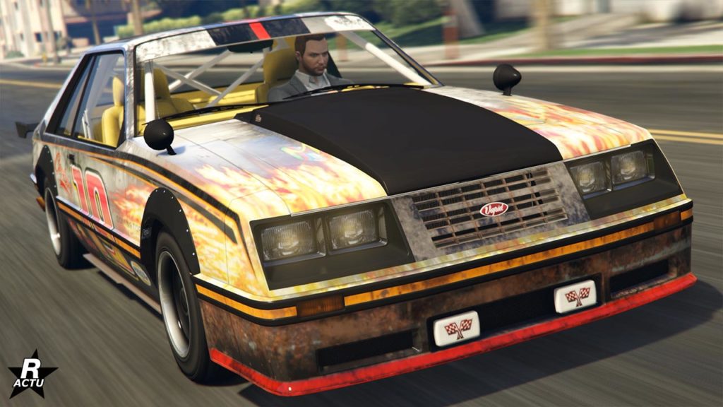 Visuel avant de la voiture Vapid Dominator FX dans le jeu vidéo Grand Theft Auto Online. La carrosserie du véhicule est peinte en blanc, mais n'est peu visible dû au fait que des décalcomanies la recouvre presque intégralement. Les calques sont des flammes jaunes avec des nuances de rouges, ainsi que des effets de carrosserie rouillée à certains endroit. Le numéro de course "19" se trouve sur chaque portières latérales. Une partie du capot se trouve bombé et en carbone noir.