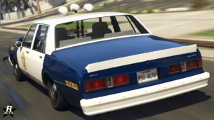 L'arrière du véhicule Declasse Impaler LX Cruiser. La voiture de police est bleu foncé et blanc. Sur le coffre, un aileron en bec de canard blanc s'y trouve.