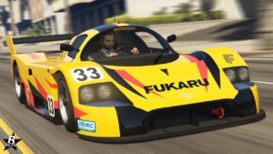 Vue avant d’une voiture de course jaune et noire, la ‘Benefactor LM87’, dans le jeu vidéo GTA Online. La voiture porte le numéro 33 et le mot ‘FUKARU’ est affiché de manière proéminente sur le devant. Le véhicule est conçu avec des caractéristiques aérodynamiques telles qu’un profil bas, de grandes prises d’air et un splitter avant.