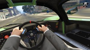 Vue intérieure depuis la perspective du conducteur à l’intérieur d’un véhicule Benefactor LM87. Le tableau de bord est équipé de diverses jauges et affichages numériques indiquant la vitesse et d’autres mesures du véhicule. Le volant a plusieurs boutons de contrôle, et il y a deux rétroviseurs latéraux teintés en vert reflétant le paysage urbain extérieur. Le pare-brise offre une vue claire de la route devant, bordée de bâtiments typiques d’un environnement urbain.