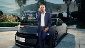 Martin Madrazo appuyé sur le capot d'une voiture du constructeur Obey passant un coup de fil à un joueur de GTA Online pour lui donner l'une de ses missions de contact.