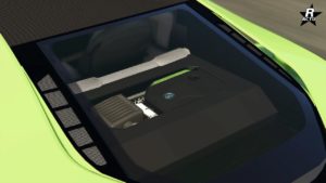L’image montre une vue rapprochée du bloc moteur d’une voiture, visible à travers la vitre arrière du véhicule Ubermacht Niobe. Le moteur est un modèle moderne avec un cache-moteur en plastique, sur lequel est apposé le logo Ubermacht. Le cache est principalement noir avec quelques accents verts assortis à la couleur extérieure de la voiture. On peut également voir des parties du moteur autour du cache, comme ce qui semble être une prise d’air ou un composant de refroidissement du côté gauche, ainsi qu’une partie du système d’échappement du côté droit.