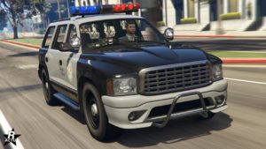 Vue avant de la voiture de police Bravado Dorado Cruiser dans GTA Online, elle est peinte en noire et gris, et sa calandre chromée a une maille rectangulaire.