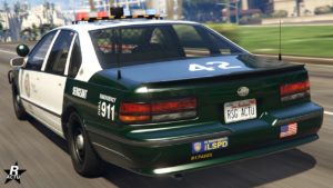 Vue arrière du véhicule de flic Declasse Impaler SZ Cruiser dans le jeu Grand Theft Auto Online. Sa carrosserie est peinte en vert et blanc, deux antennes pour la radio de police sont présentes sur le coffre de chaques cotés.