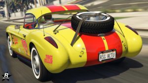 Vue arrière de l'Invetero Coquette D1, la voiture est de couleur jaune avec des bandes rouges. Sur le coffre, une roue de secours est présent.