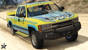 Image du Declasse Yosemite 1500 vue de devant. Le véhicule de GTA Online est de couleur jaune et bleu, et est équipé du skin exclusif à GTA+ "Motif abstrait bleu" sur sa carrosserie.