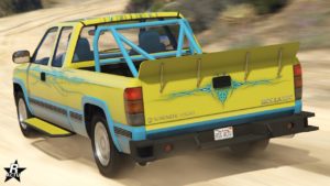 Image du tout-terrain Declasse Yosemite 1500 vue de l'arrière. La voiture américaine circule sur une chemin de sable dans GTA Online et est peint en jaune et bleu. Un aileron en forme de bec de canard est présent à l'arrière du plateau.