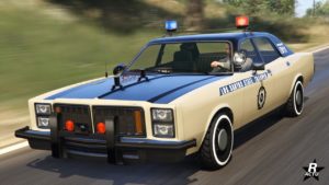 Vue de l'extérieur avant droit de la voiture de police Bravado Greenwood Cruiser dans le jeu vidéo GTA Online, elle est de couleur beige avec des parties noires sur le dessus. Sur le capot, un écriteau "police" est écrit et "Police d'État de Los Santos" sur les portières.