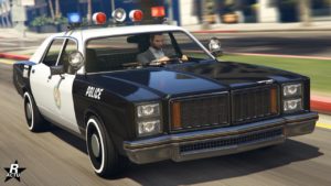 Vue avant du véhicule Bravado Greenwood Cruiser dans GTA Online. Sa peinture est en duochrome blanc et noir avec écrit "police" en blanc sur les côtés latéraux avant. Le symbole de la ville de Los Santos est également présent sur les portières.