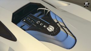 Vue du capot arrière du véhicule Ocelot XA-21 dans GTA Online. On peut apercevoir à travers une vitre du capot, le moteur entouré de carbone, ainsi que le logo du constructeur britannique Ocelot et le nom de la voiture inscrit sur le dessus du moteur.