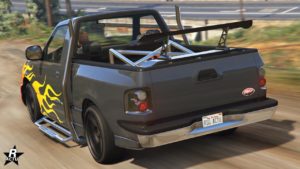 Image de l'arrière de la voiture de type tout-terrain Vapid Firebolt ASP dans le jeu de Rockstar Games, GTA Online. Le véhicule est peint en gris, à l'arrière un plateau est présent où se trouve une cage de renforcement chromée.