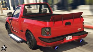 L'arrière de la voiture de type tout-terrain Vapid Firebolt ASP dans GTA Online. Le véhicule américain est peint en rouge, un aileron de type dragster est présent à l'arrière du plateau qui est vide.