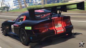 Vue arrière de la Bravado Banshee GTS, elle est peinte en noire avec des décalcomanies de courses rouges, un très grand aileron agressif en carbone est fixé à l'arrière du véhicule de GTA Online.
