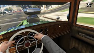 Image dévoilant le point de vue du conducteur lors de la conduite de la voiture Albany Roosevelt Valor dans GTA Online. Le tableau de bord est visible et est confectionné en bois, une partie de la vue sur la route est obstruée par le turbocompresseur du moteur qui dépasse du capot.