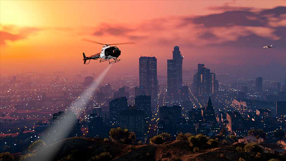 Bannière d'article de GTA Online. L'image représente une vue de la ville de Los Santos en jeu sous un couché de soleil, un hélicoptère de police traverse le ciel.