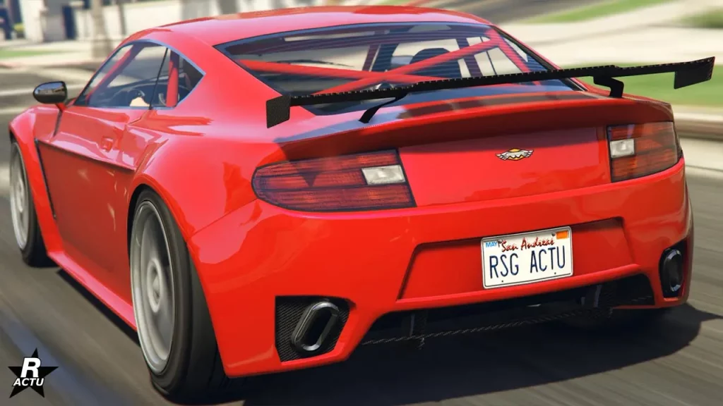 Vue arrière de la sportive Dewbauchee Rapid GT sur une route de GTA Online. La voiture britannique est peinte en rouge, a un petit aileron en carbone fixé sur le coffre et il est possible d'apercevoir les arceaux de sécurité par le pare-brise arrière, où les arceaux forment un croix derrière les sièges dans l'habitacle.
