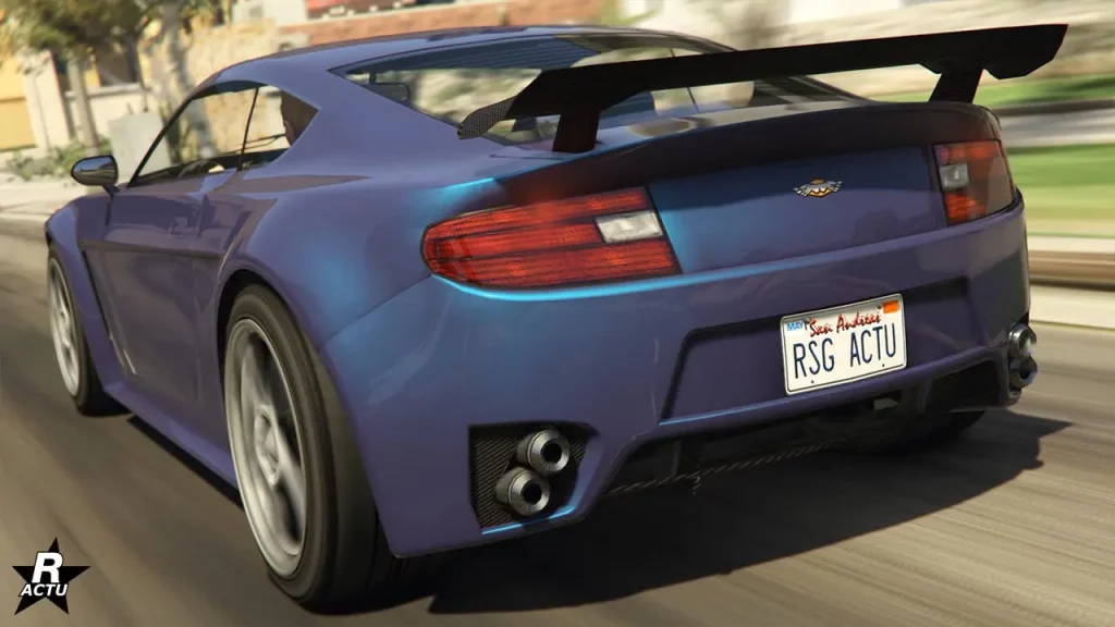 L'arrière du bolide anglais Rapid GT sur une route du jeu vidéo GTA Online de Rockstar Games. La voiture dispose d'une couleur mauve sur sa carrosserie, avec quelques reflets bleutés. Un aileron GT en carbone se trouve fixé sur le dessus du coffre et deux doubles pot d'échappement circulaire sont incrustés dans le pare-chocs arrière.