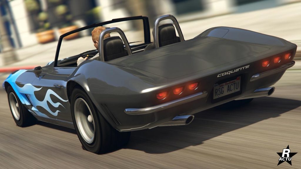 Image de l'arrière de la voiture de sport de collection Coquette classique dans le jeu vidéo GTA Online. Sa peinture est grise anthracite, ne possède pas de toit et on peut apercevoir une décalcomanie de flammes bleues sur les cotés vers l'avant.