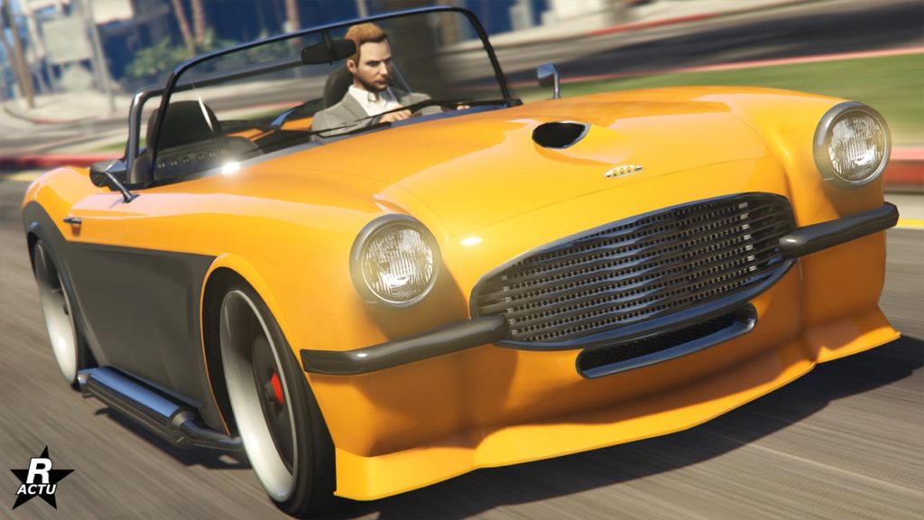 Présentation de l'avant de la voiture américaine ancienne de type grosse cylindrée, Coquette BlackFin, dans le jeu vidéo GTA Online. Sur l'image, sa carrosserie est de couleur jaune pour la partie supérieure et la face avant, tandis que les côtes latéraux sont peints en gris anthracite. Le véhicule qui s'inspire d'une Chevrolet Corvette C1 est dans sa version décapotable où le toit est retiré.
