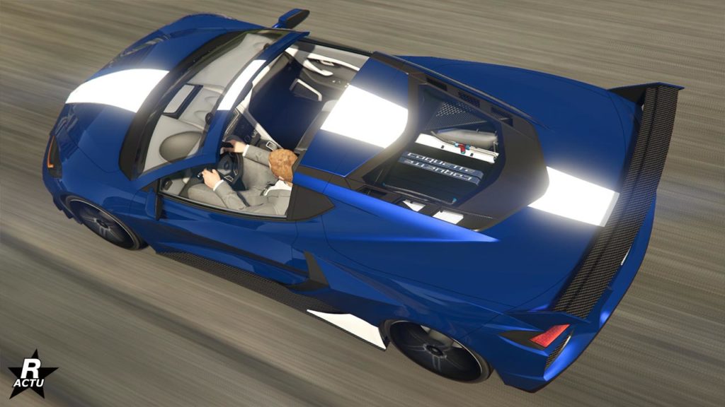 Vue du dessus de l'Invetero Coquette D10 sur une route de GTA Online. Le toit du véhicule a été retiré, laissant apparaitre l'habitacle. À travers la lunette arrière, il est également possible d'apercevoir le moteur du véhicule, qui ce dernier, est peint en bleu avec une décalcomanie d'une bande blanche traversante.