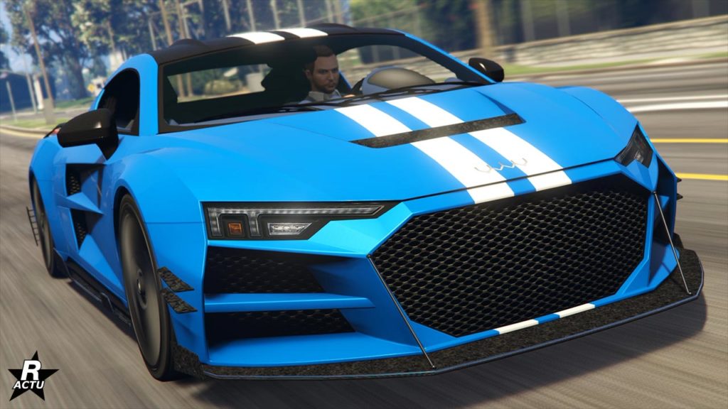Image présentant la voiture allemande Obey 10F avec une vue avant sur une route du jeu vidéo GTA Online. Le bolide qui s'inspire d'une Audi R8 4S est peint en bleu avec une double bande blanche qui traverse toute la carrosserie verticalement au centre. Le toit est fait de fibres de carbone avec un appui aérodynamique.