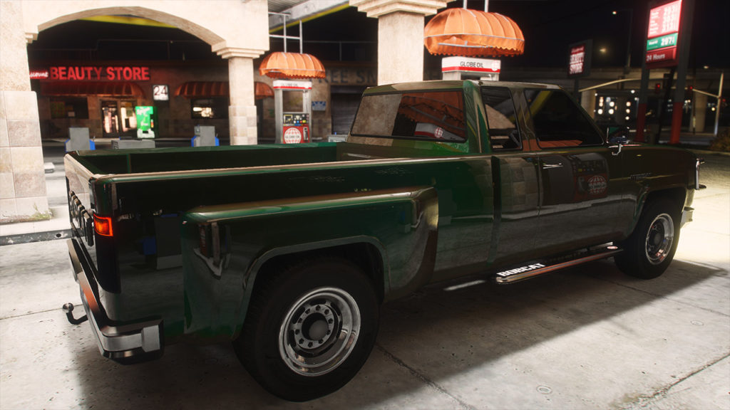 Image de nuit d'un véhicule vert dans Grand Theft Auto V, sous l'abris d'une station service éclairée et où la carrosserie du véhicule reflète les alentours.