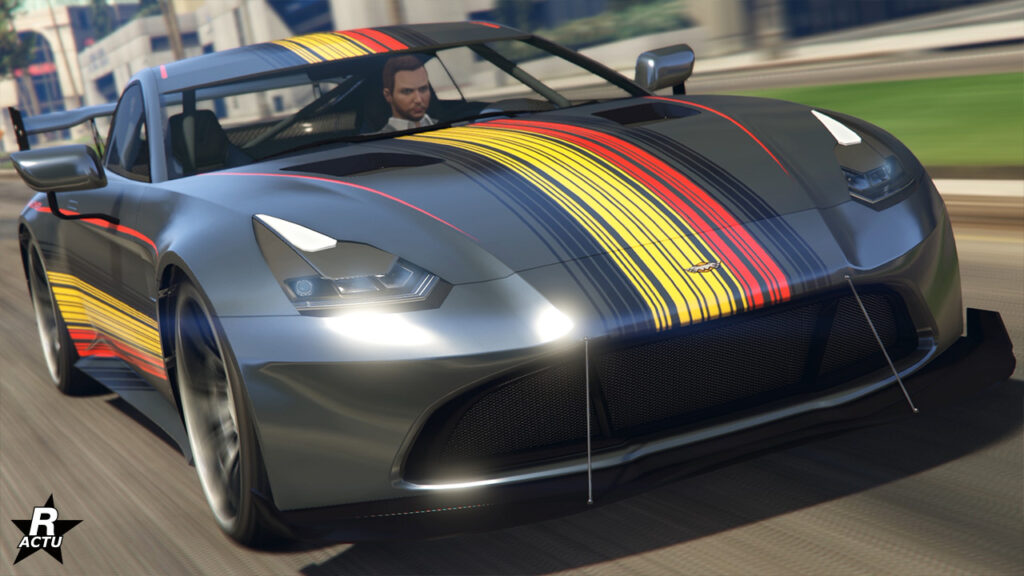 L'avant de la voiture Dewbauchee Rapid GT X dans le jeu GTA Online. La carrosserie est peinte en gris métallisé avec une décalcomanie de bandes verticales aux couleurs du drapeau allemand (noire, jaune et rouge) sur le capot.