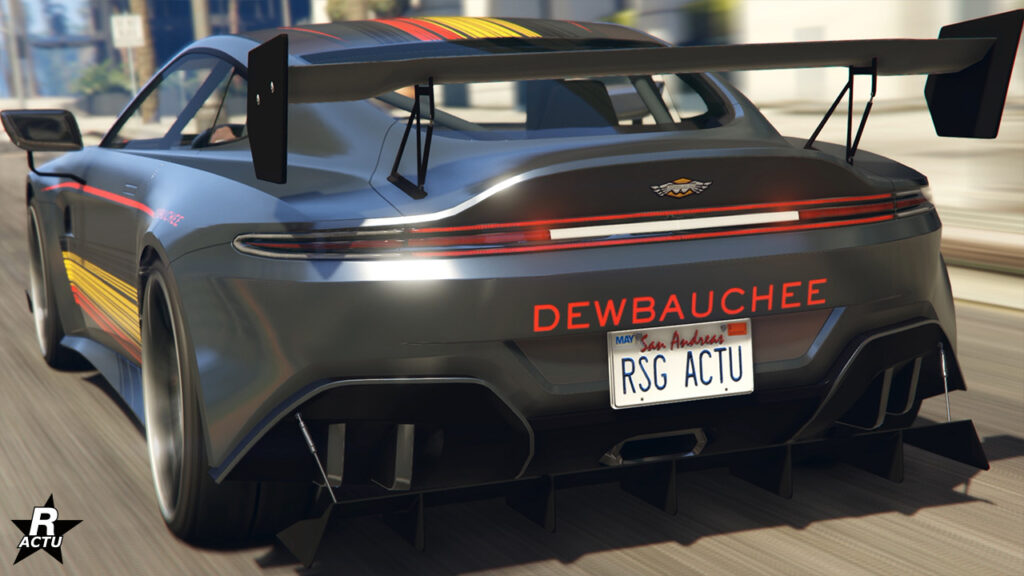Face arrière de la sportive britannique Rapid GT X - Sa peinture est gris foncé et un autocollant rouge "Dewbauchee" du nom du constructeur, se trouve entre le pare-chocs arrière et ses phares. Un grand aileron GT de course se trouve quant à lui sur le dessus du coffre.