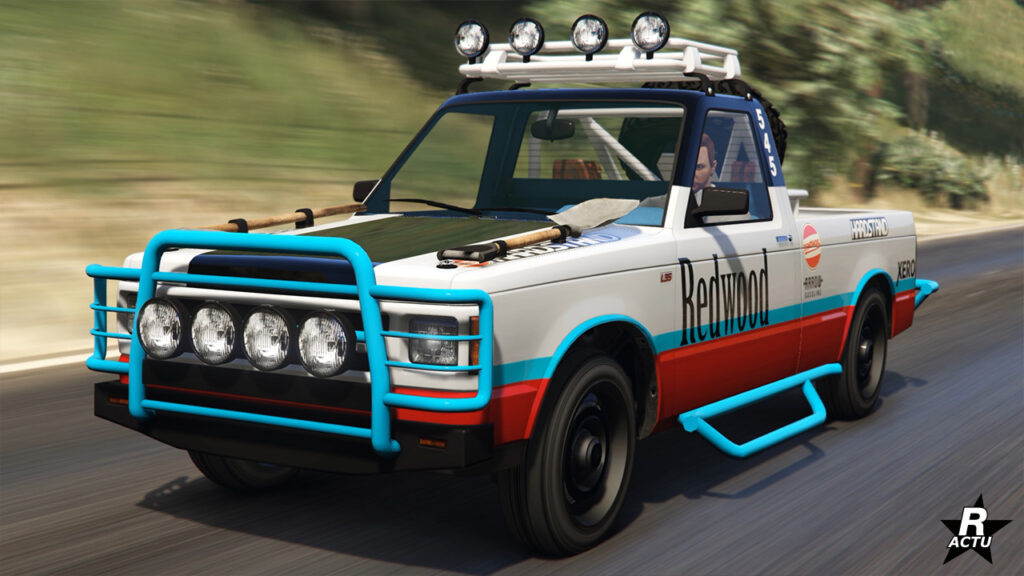 Pick-up tout-terrain "Declasse Walton L35 de série" vue de devant. Le bolide américain est peint en gris et a un bare-buffles bleu avec des projecteurs intégrés, tout comme la guérite au-dessus de la cabine.