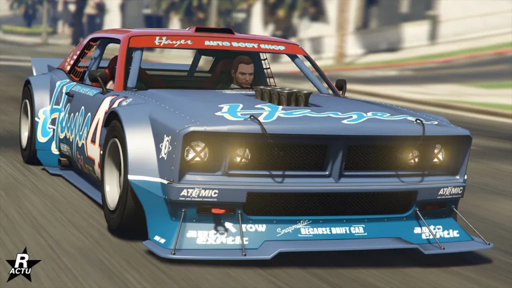 Vue avant de la voiture de sport américaine, Declasse Tampa drift, sur une route du jeu vidéo Grand Theft Auto Online. La carrosserie du bolide est peinte en bleu nautique avec le toit en rouge. Elle possède des autocollants, dont celui de la compagnie "Hayes" s'affichant sur l'avant du capot, ainsi que divers sponsors sur le pare-chocs avant.