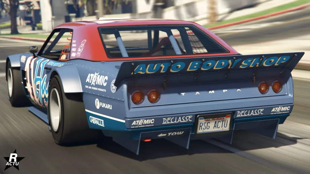 Image offrant une vue arrière du bolide Tampa drift du constructeur américain Declasse. Le véhicule de GTA Online est peint en bleu nautique pour une grande partie de la carrosserie, et en rouge pour celle du toit. Divers autocollants sont accolés, dont "Auto Body Shop" à l'arrière de l'aileron en bec de canard, en référence à l'atelier Hayes. Mais aussi divers sponsors , dont "Atomic" ou encore "Fukaru" en blanc.