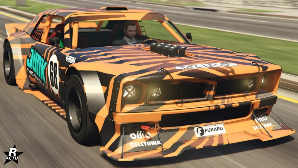 Image donnant un aperçu de la voiture "Declasse Tampa drift" avec une vue avant sur une route ensoleillée du jeu vidéo GTA Online. Le bolide est intégralement peint en orange avec des décalcomanies zébrées noires sur sa carrosserie, avec le logo bleu "Junk" sur les portières latérales.