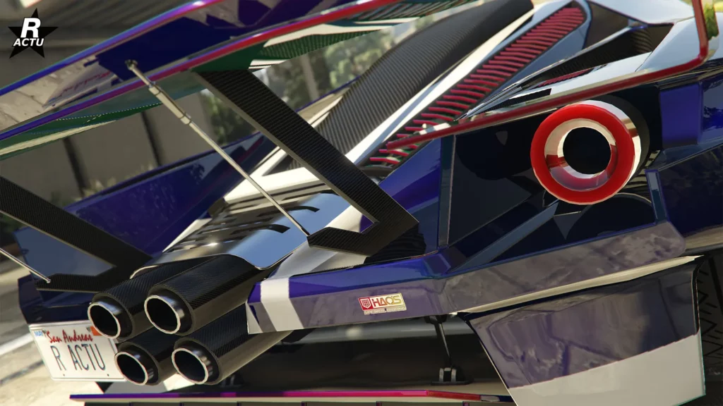 Vue rapprochée de l’arrière de la supercar Vapid FMJ MK V, inspirée de la Ford GT Mk IV, dans GTA Online. Cette perspective permet d’observer de plus près le phare arrière circulaire, les quatre pots d’échappement au revêtement en carbone, ainsi que la calandre à lames horizontales aux nuances de rouge, intégrée entre le capot moteur, également en carbone.