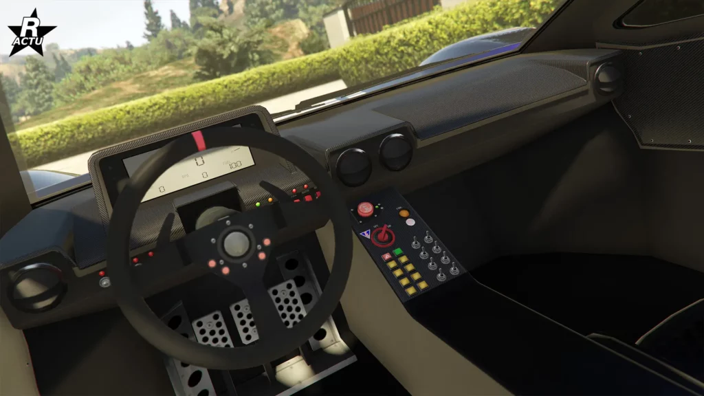 Vue de l’habitacle de la supersportive Vapid FMJ MK V dans le jeu vidéo GTA Online. La partie supérieure du tableau de bord est en fibre de carbone. Un écran numérique rectangulaire est encastré dans le tableau de bord, derrière le volant, pour indiquer la vitesse du véhicule. Dans la console centrale se trouvent divers boutons et interrupteurs, dans un style inspiré de la compétition automobile.
