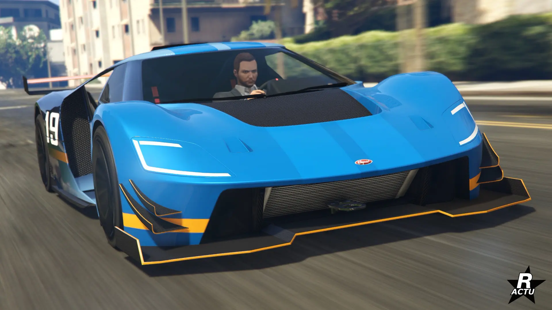 Vue avant de la super car Vapid FMJ MK V, le bolide de course est peint en bleu avec une fine bande jaune au niveau du bas de caisse.