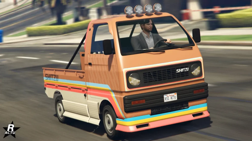 L'avant du véhicule utilitaire japonais Shitzu Keitora, de couleur orange avec des bandes latérales rétros.