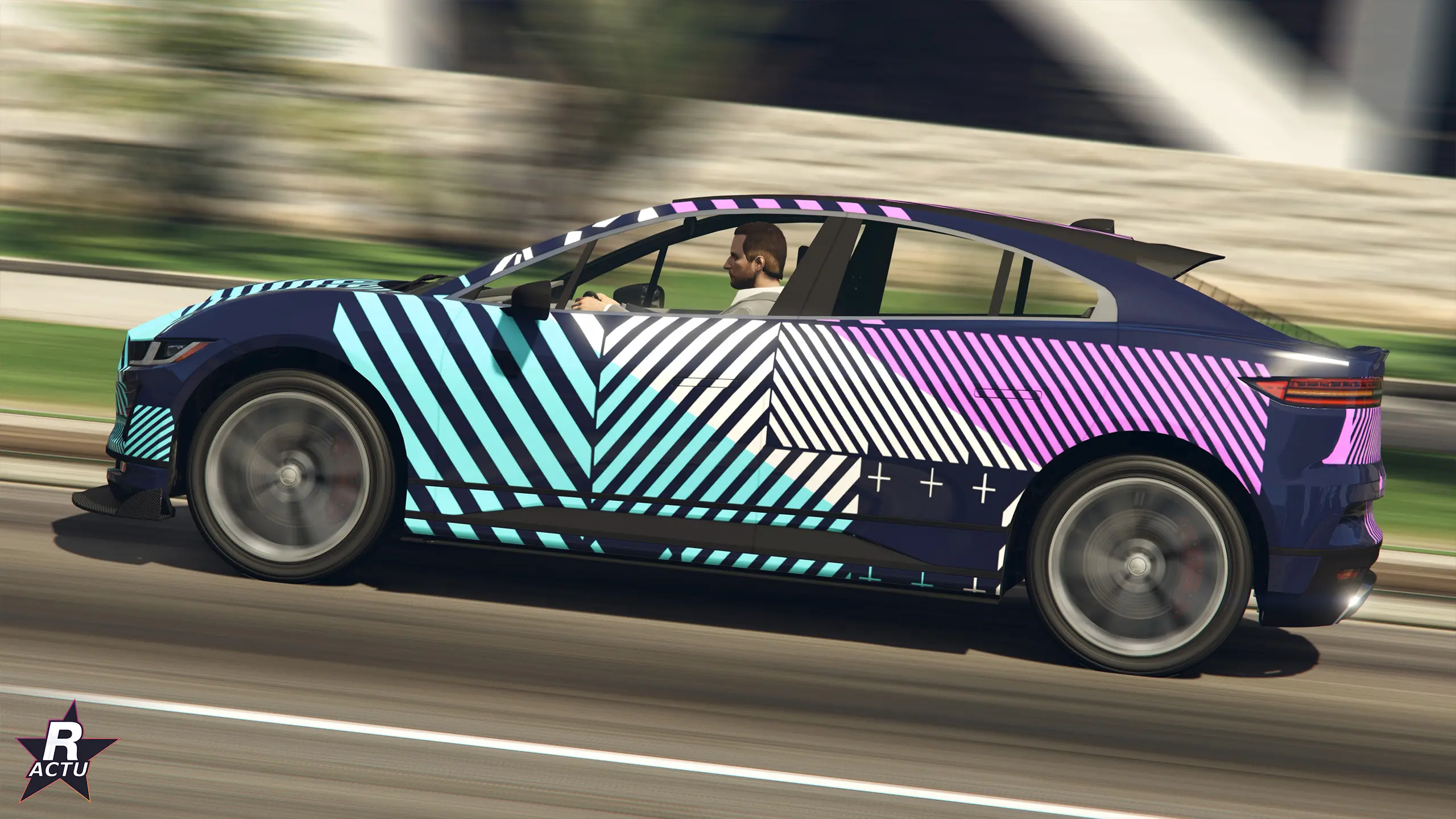 Ocelot E-Stride de profil en livrée graphique cyan, rose et blanche, lancée sur une route