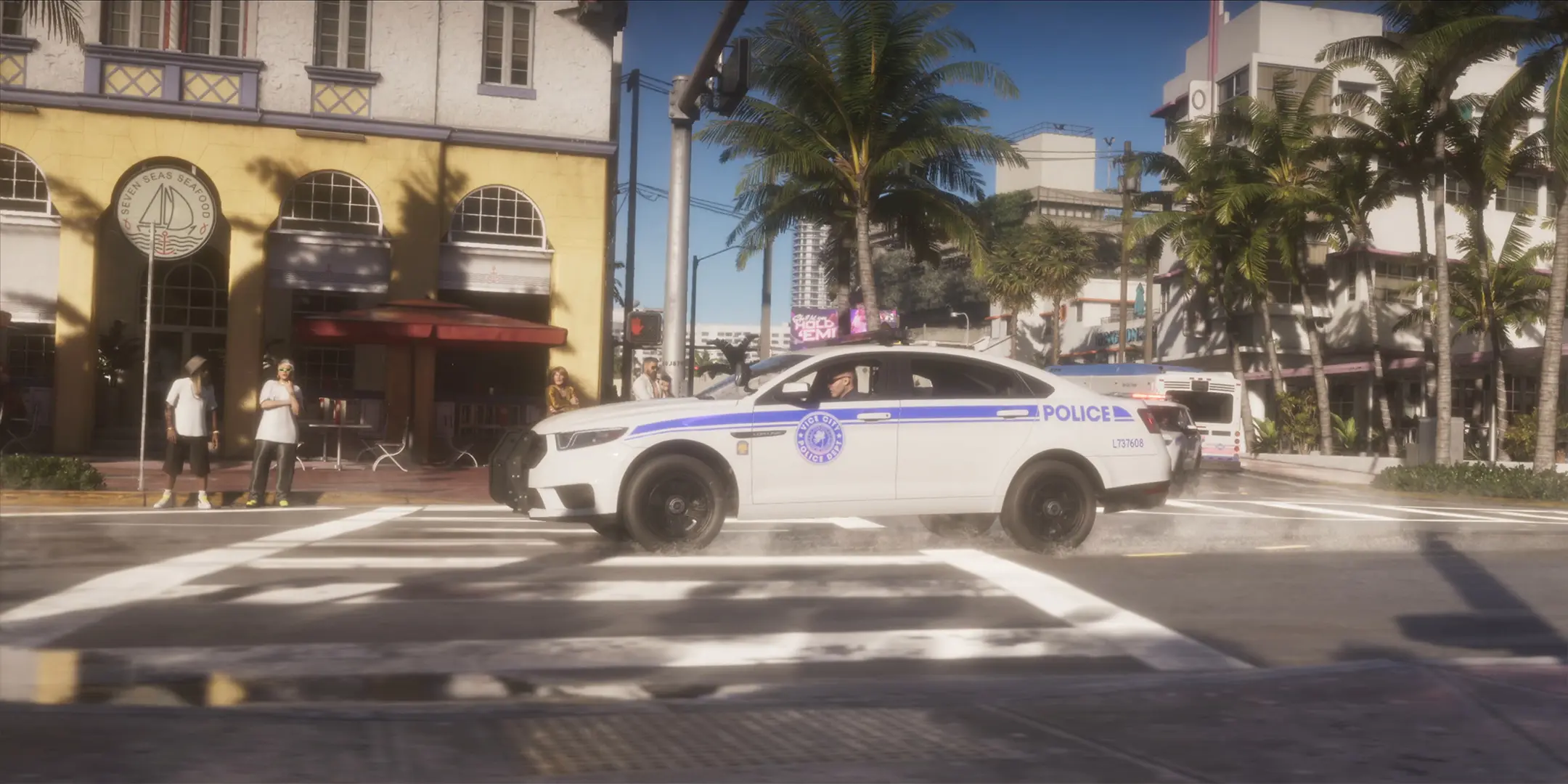Voiture de police blanche, avec le logo de la "Vice City Police Departement" sur sa portière, roulant dans la ville principale de GTA VI.